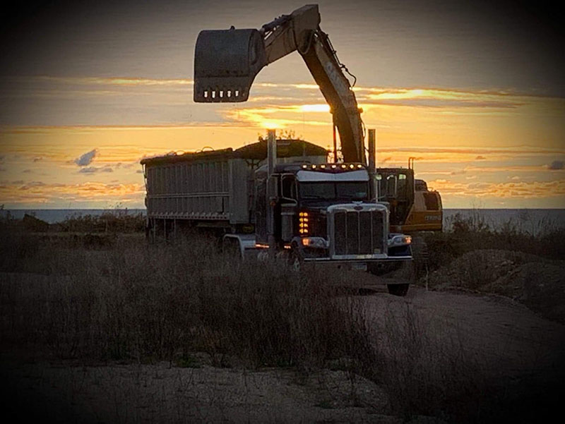 collecting dry bulk in end dump trailer bed at sunset